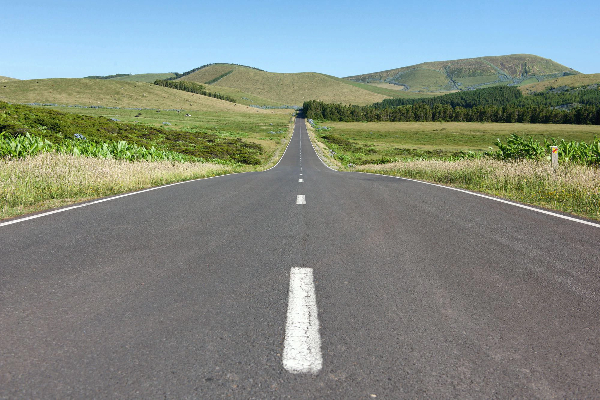 Eine einsame Straße durchschneidet das hügelige Hochland